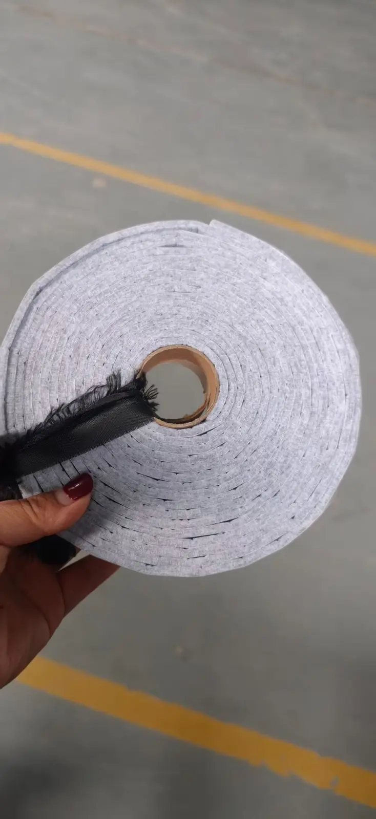 Light gray self-adhesive felt strip in roll form